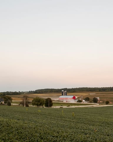 Wide green Pennsylvania farmland with barn and silo under a pale evening sky