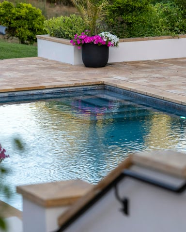 Outdoor swimming pool with stone patio and flowering garden